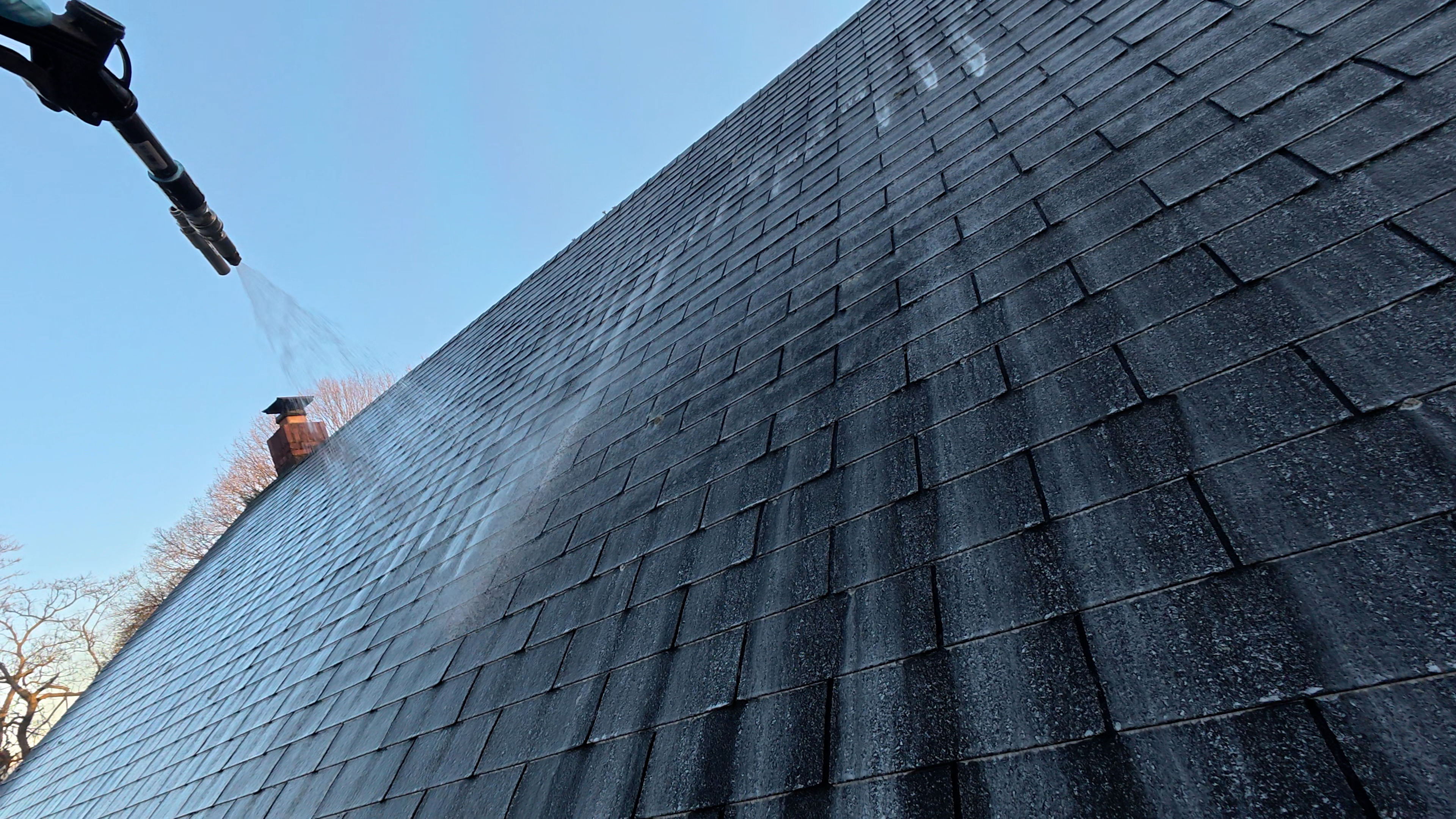 Roof being cleaned with a spray application