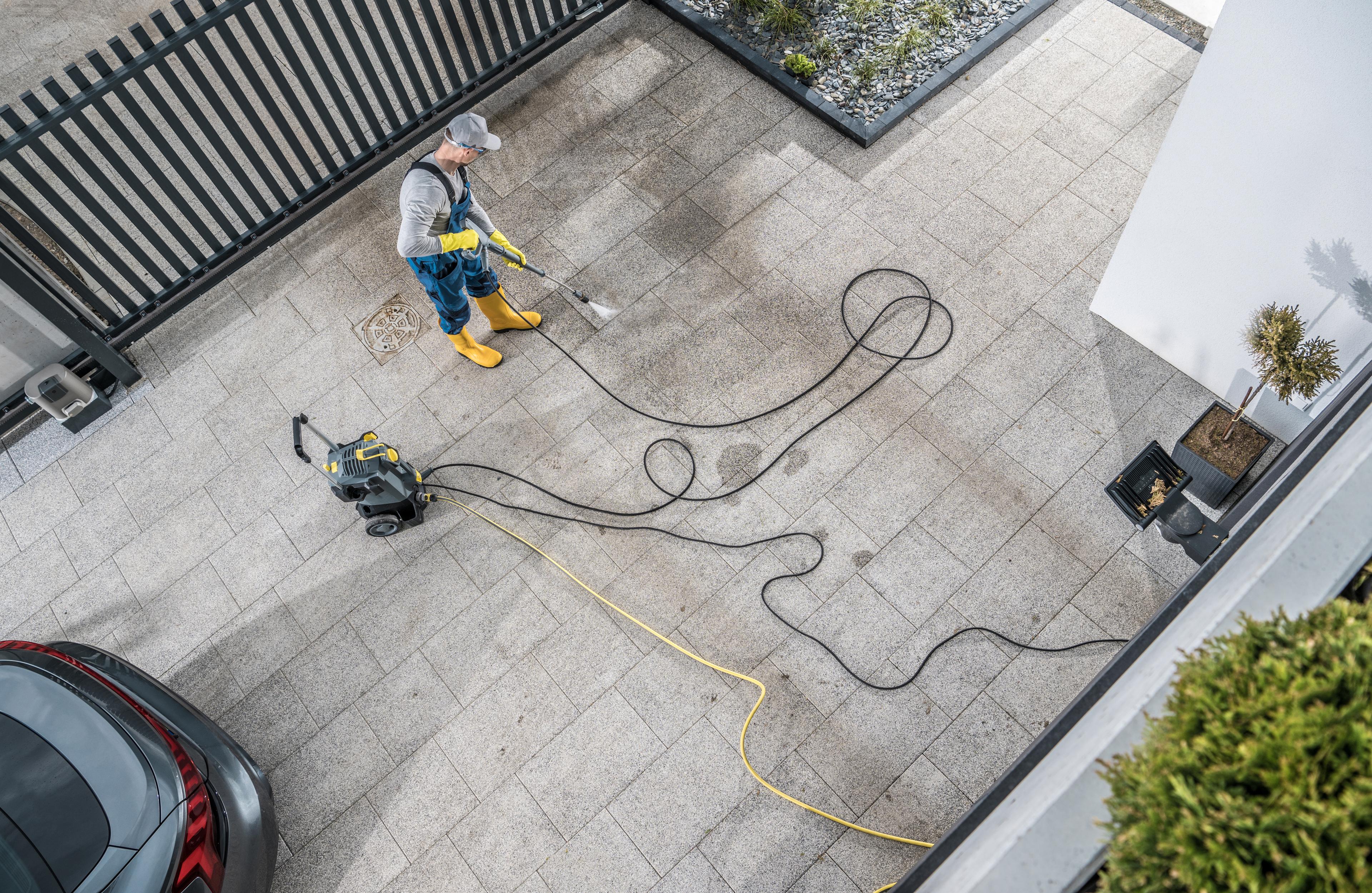 Technician pressure washing a paved outdoor surface